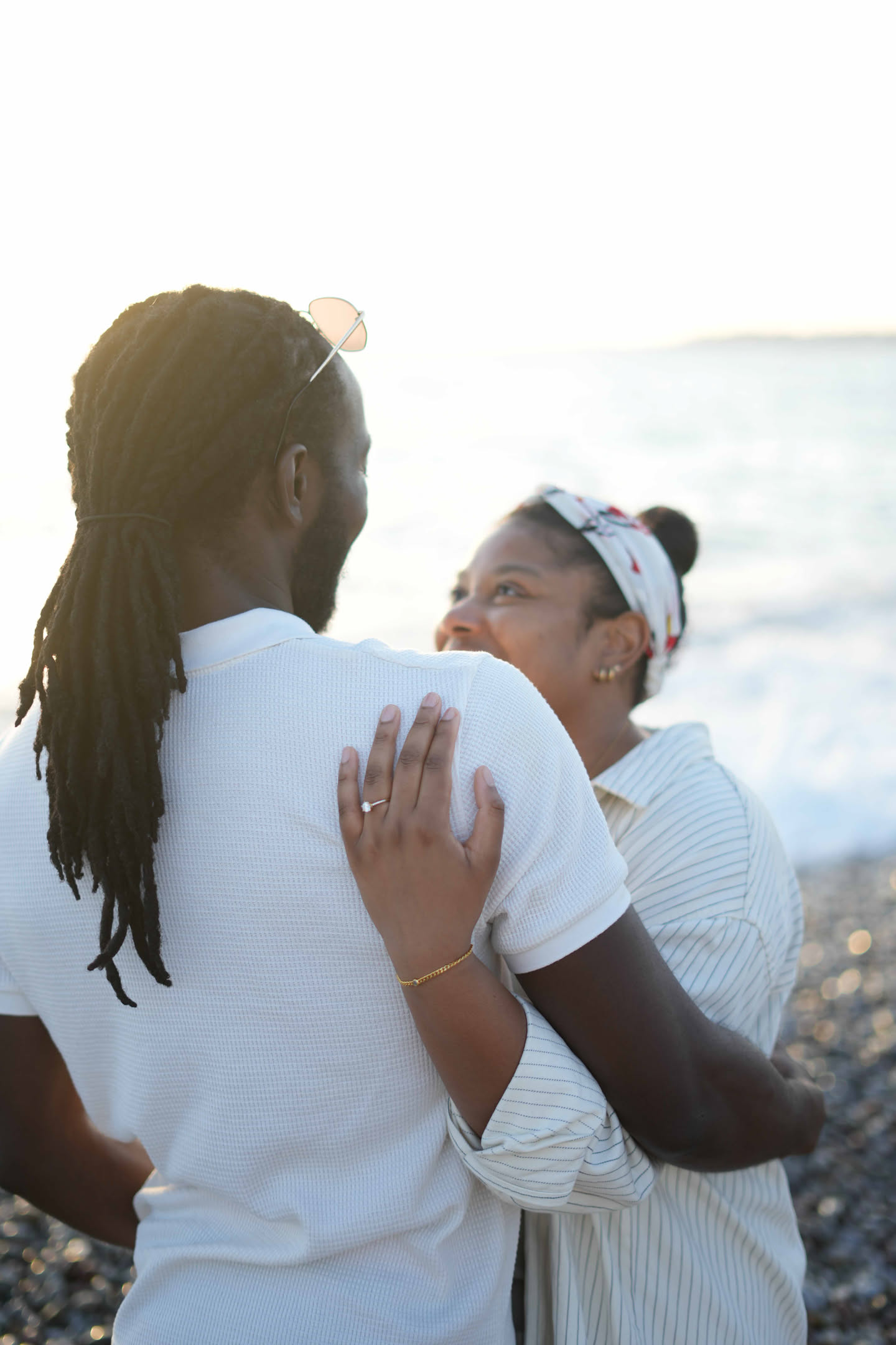 Mike and Lareece embracing by the sea with Lareece’s engagement ring visible
